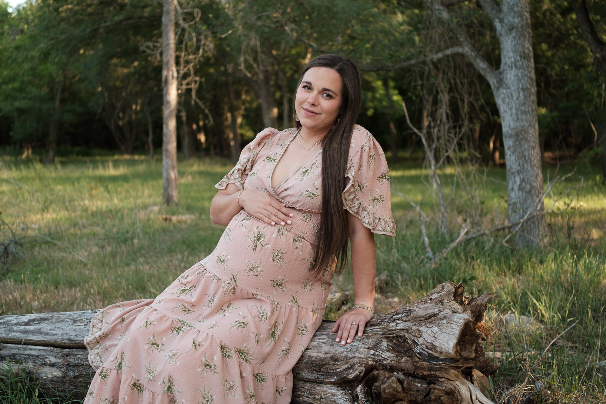 posed pregnant woman sitting on a tree log