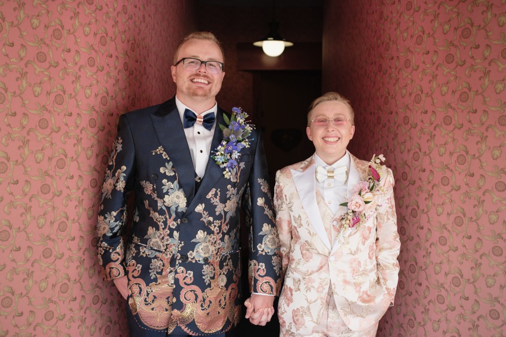 Wedding couple portrait against iconic pink wallpaper at Madonna Inn captured on Fuji X-T30 with Viltrox 25mm f1.7 AIR lens.