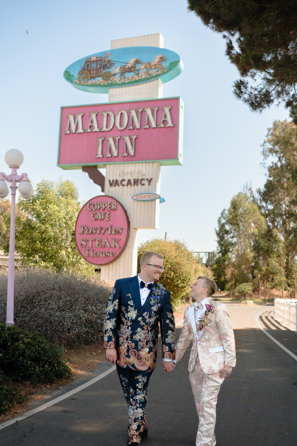 Couple walking in front of iconic Madonna Inn sign photographed during wedding portraits using Fuji X-T30 sample setup.