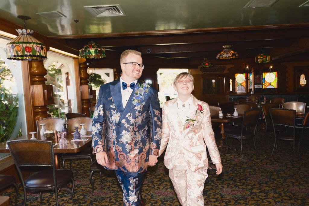 Bride and groom walking through Madonna Inn hallway photographed with Fuji XF 18mm f2 creating cinematic wedding moment.